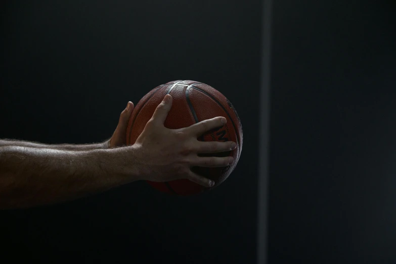 a man holding a basketball in his hand, by David Simpson, unsplash, on a black background, made in unreal engine 5, indoor shot, panels