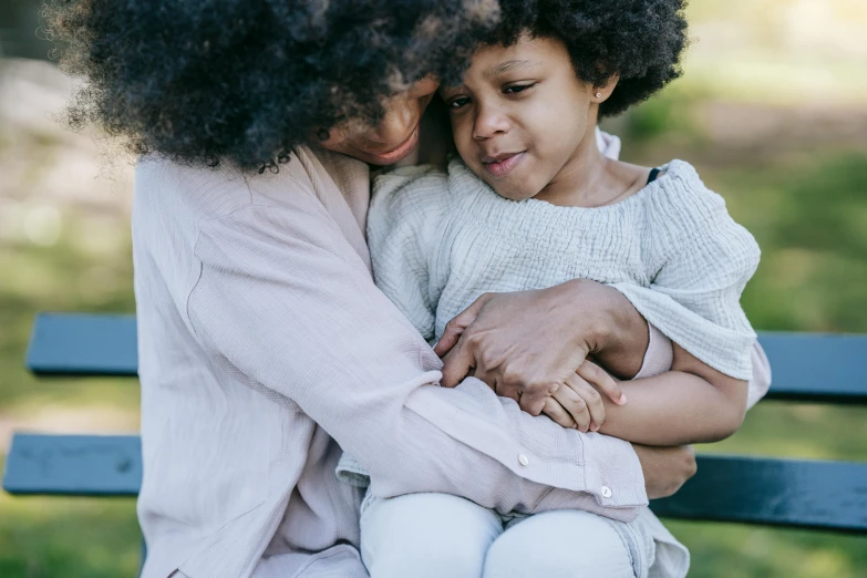 a woman and a child sitting on a bench, pexels contest winner, embracing, curly afro, manuka, high quality detail