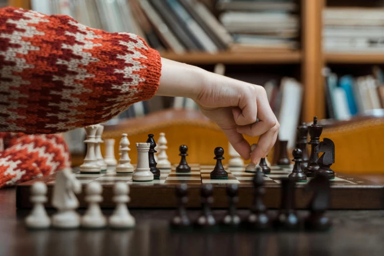 a person playing a game of chess on a table, by Sylvia Wishart, unsplash contest winner, librarian, fan favorite, back of hand on the table, modelling