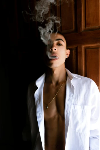 a man in a white shirt smoking a cigarette, an album cover, inspired by Carlos Berlanga, unsplash, non binary model, wiz khalifa, smokey room, light skin