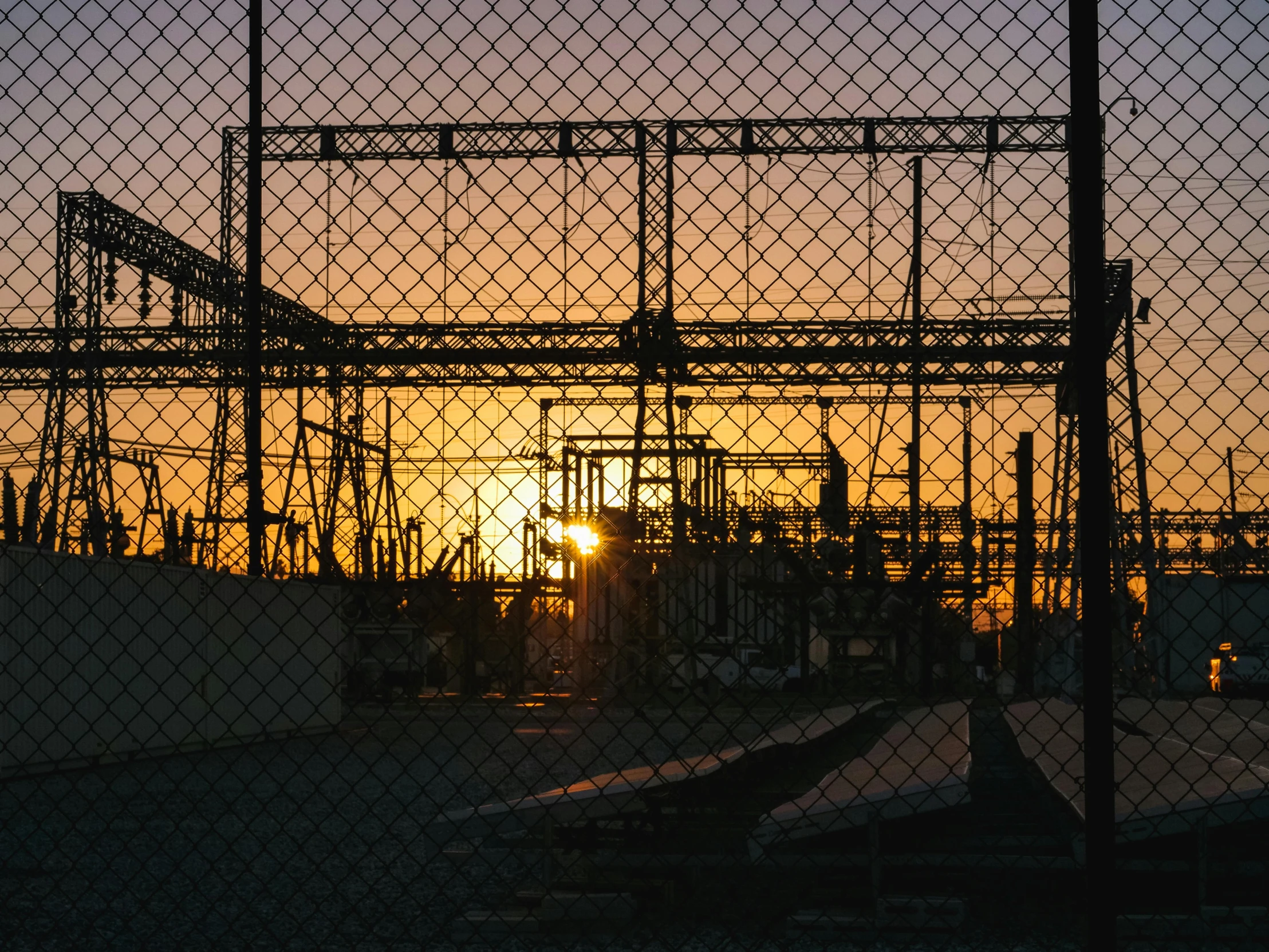 the sun is setting behind a chain link fence, a picture, inspired by Elsa Bleda, pexels contest winner, power plants, petrol aesthetic, worksafe. instagram photo, electricity archs