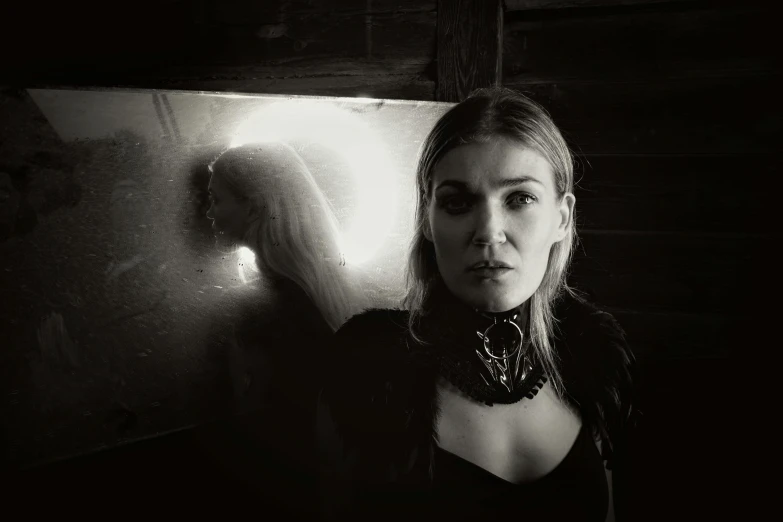 a black and white photo of a woman leaning against a wall, inspired by Elsa Bleda, unsplash, surrealism, rosamund pike as the doctor, standing in front of a mirror, portrait of a dark witch, portrait of emma frost