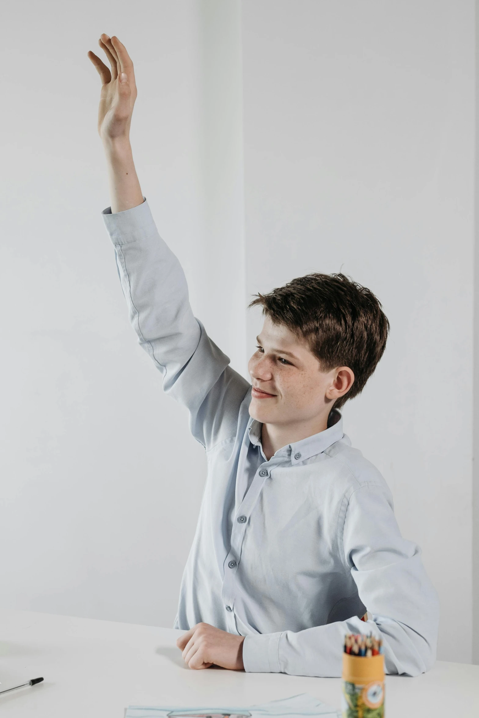 a man sitting at a desk in front of a computer, raising an arm, declan mckenna, on a gray background, happy kid