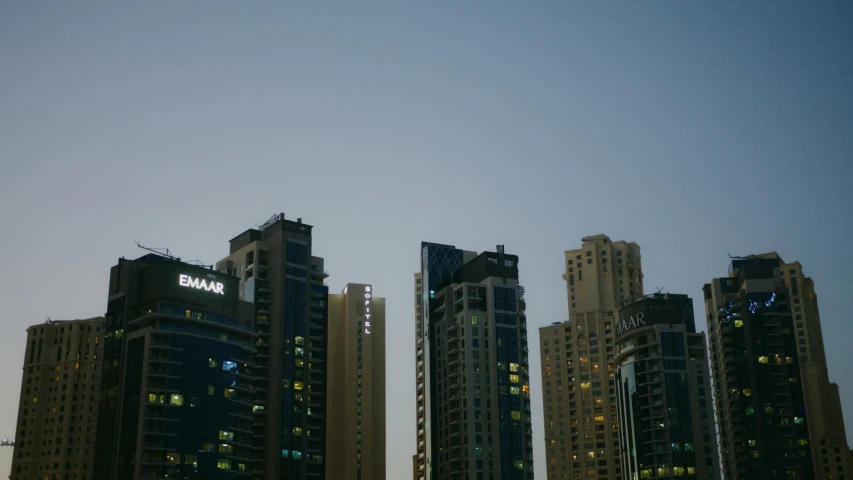 a group of tall buildings sitting next to each other, in the evening, dubai, taken on a 2010s camera, far - mid shot