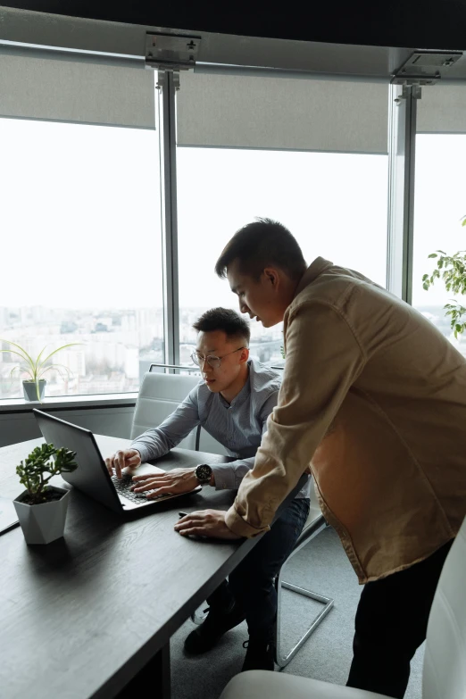 a couple of men sitting at a table with a laptop, standing on a desk, on top of it, large windows, ui and ux