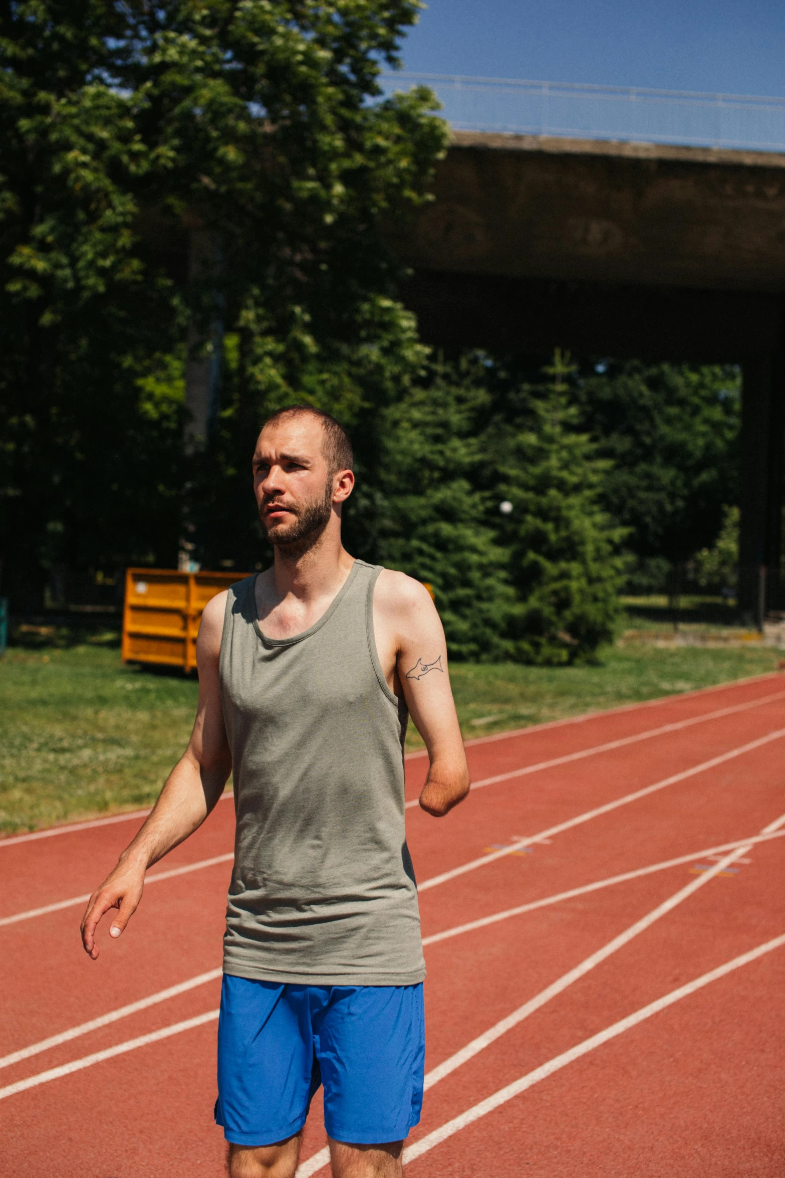 a man standing on a track holding a frisbee, by Attila Meszlenyi, wearing a tank top and shorts, 2019 trending photo, pacing, promo image