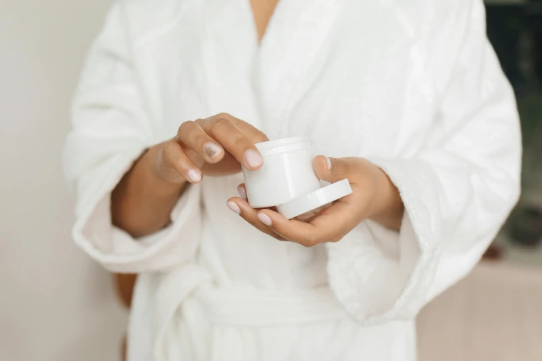 a woman in a bathrobe holding a jar of cream, trending on pexels, detailed white, upper body image, petite, uploaded