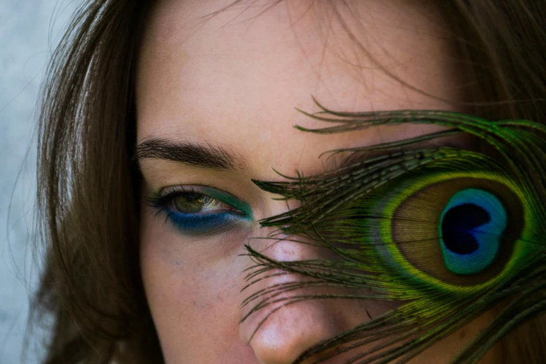 a close up of a woman with a peacock feather on her eye, an album cover, inspired by Elsa Bleda, pexels contest winner, renaissance, taken with canon 5d mk4, human with one robot eye, colored photo, bird view