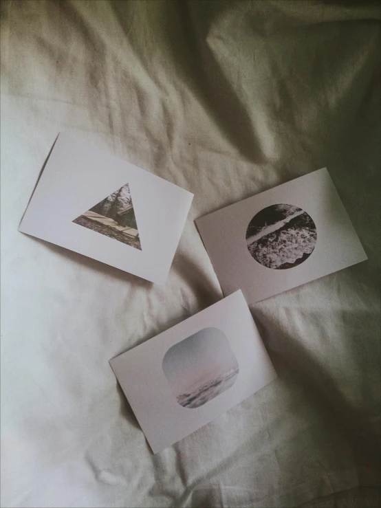 a bunch of cards sitting on top of a bed, a polaroid photo, by Christen Dalsgaard, unsplash, mail art, three moons, landscape of geometric shapes, delicate patterned, triptych