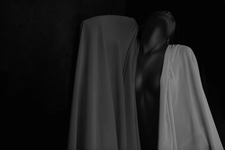 a black and white photo of a mannequin, inspired by Carrie Mae Weems, pexels contest winner, figurative art, halloween ghost under a sheet, dark skin female goddess of love, breasts covered and sfw, man is with black skin