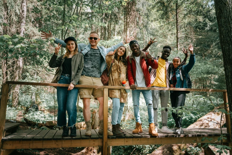 a group of people standing on a bridge in the woods, pexels, renaissance, diverse faces, camp, avatar image, friendly