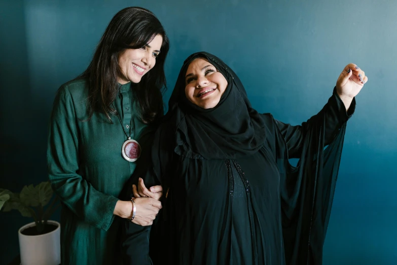 a couple of women standing next to each other, inspired by Maryam Hashemi, pexels contest winner, hurufiyya, press shot, shohreh aghdashloo, middle eastern, with long