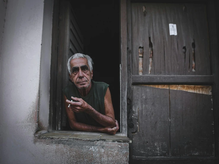 a man that is looking out of a window, by Elsa Bleda, pexels contest winner, hyperrealism, cuban setting, a silver haired mad, a wooden, outside alone smoking weed