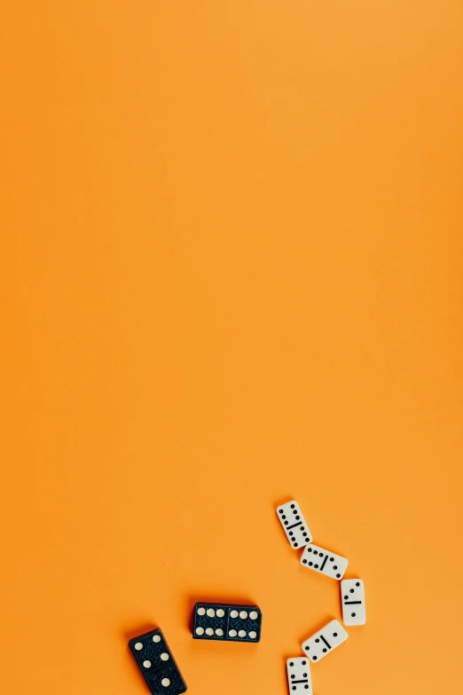 a group of dominos sitting on top of an orange surface, an album cover, by Joseph-Marie Vien, conceptual art, ffffound, popular on behance, rolling dice, [ overhead view of a table ]!!