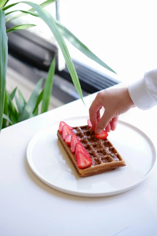 a white plate topped with a waffle covered in strawberries, inspired by Barthélemy Menn, unsplash, sleek hands, 4yr old, ignant, caramel