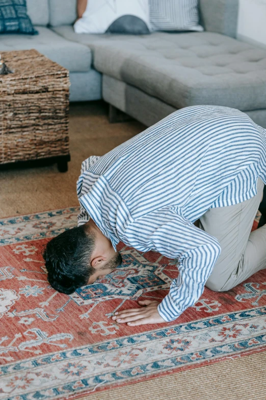 a man kneeling on a rug in a living room, by Carey Morris, pexels contest winner, hurufiyya, praying posture, stretch, arched back, modest