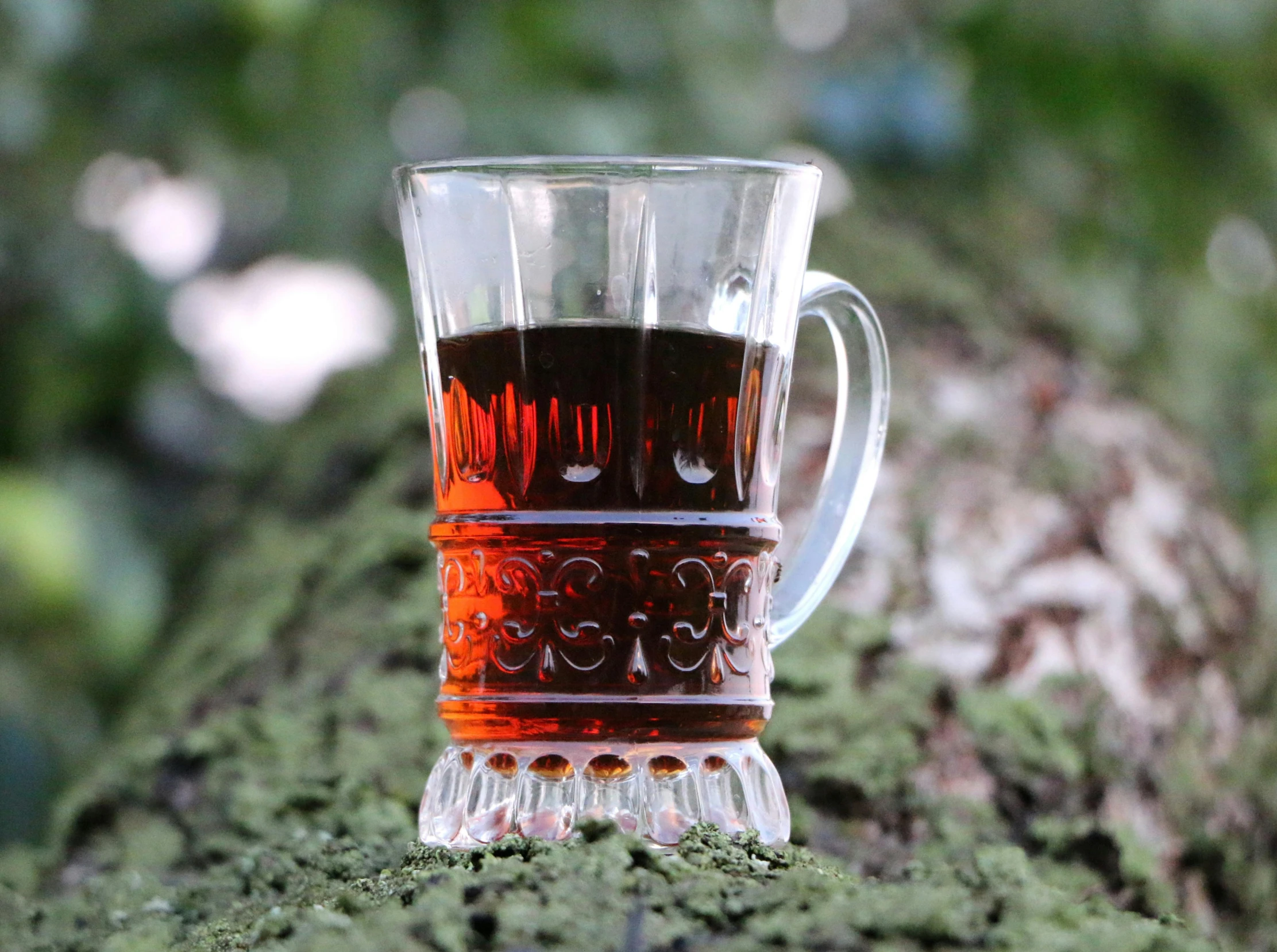 a cup of tea sitting on top of a tree trunk, pixabay, hurufiyya, glass with rum, slavic style, reddish - brown, fully symmetrical