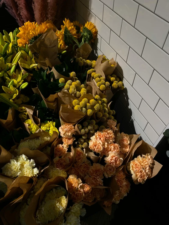 a bunch of flowers sitting on top of a counter, yellows and blacks, photo for a store, ready to eat, exterior shot