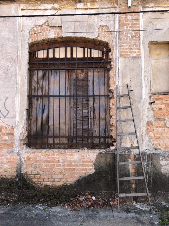 a ladder leaning against the side of a building, pexels contest winner, behind bars, old abandoned building, that we would see in the essoldo, view from across the street