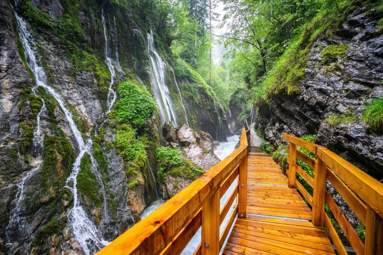 a wooden walkway leading to a waterfall, by Julia Pishtar, shutterstock, slovenian, instagram post, wet climate, balcony