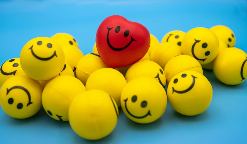 a red ball sitting on top of a pile of yellow balls, a picture, pexels, toyism, happy smiley, hearts, blue, high quality photo