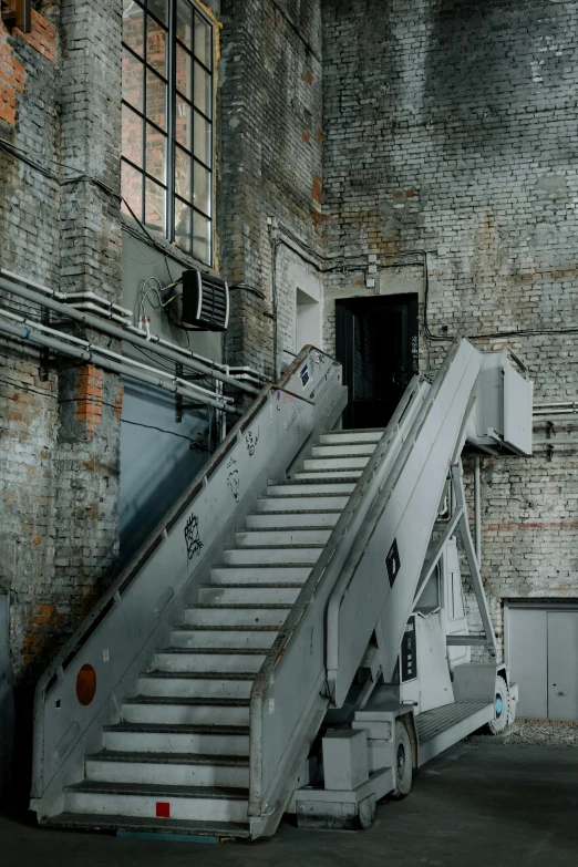 a man riding a skateboard up the side of a ramp, inspired by Thomas Struth, grey warehouse background, stairs to an upper floor, industrial machinery, theater access corridor