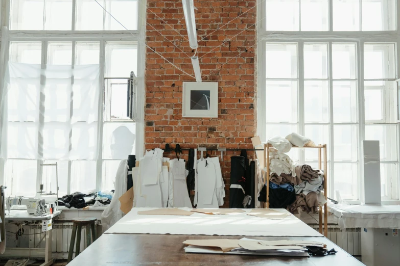 a table that has a bunch of clothes on it, trending on unsplash, process art, big windows, 9 9 designs, industrial space, fiona staples