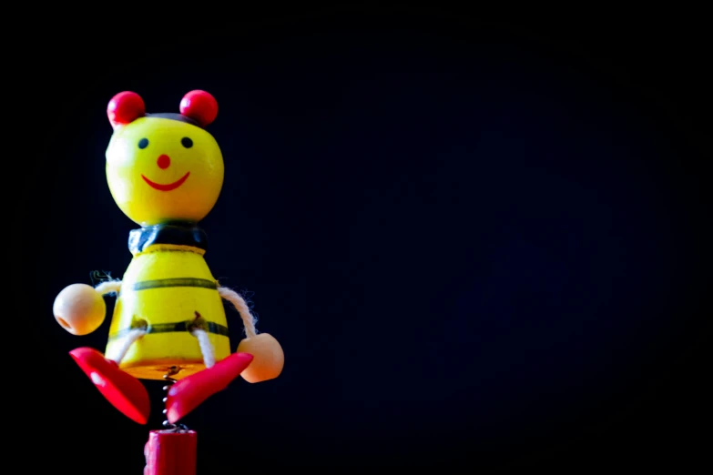 a close up of a toy figurine of a bee, an album cover, by Jesper Knudsen, pexels, standing with a black background, happy smile, half wooden pinocchio, 15081959 21121991 01012000 4k