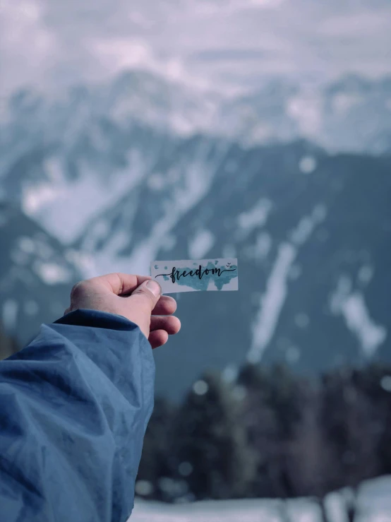 a person holding a knife with mountains in the background, by Emma Andijewska, pexels contest winner, graffiti, minimalist sticker, frosted glass, faked ticket close up, freedom