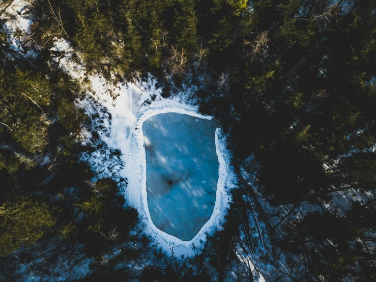 a frozen lake in the middle of a forest, pexels contest winner, land art, sinkhole, a high angle shot, perfect shape, low detailed