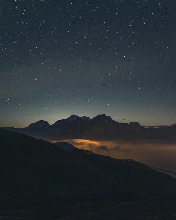 a person standing on top of a mountain under a night sky, by Karl Stauffer-Bern, distant mountain range, muted lights, slightly pixelated, instagram post