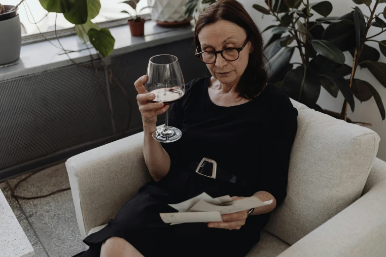 a woman sitting on a couch holding a glass of wine, pexels contest winner, renaissance, white reading glasses, in kaethe butcher, carefully crafted, ute osterwalder