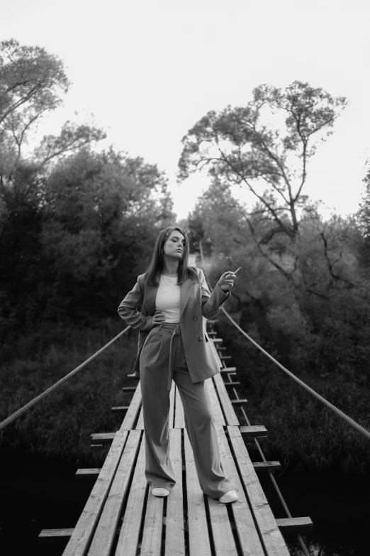 a black and white photo of a woman on a suspension bridge, by Alexis Grimou, low quality photo, girl in a suit, wood bridges, selfie of a young woman