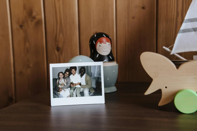 a photo frame sitting on top of a wooden table, a polaroid photo, inspired by Sarah Lucas, with tiny people, home display, 80s photo, shaped picture