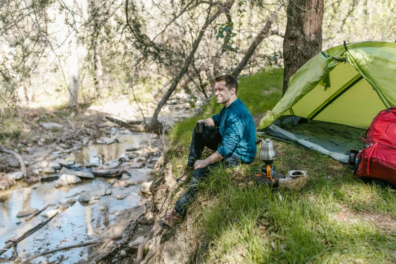 a man sitting in front of a tent next to a creek, a green, avatar image, campsites, lookbook