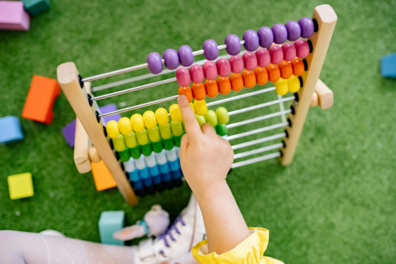 a little girl is playing with an abacuse, trending on pexels, algebra, multi colour, holding a wooden staff, top down shot