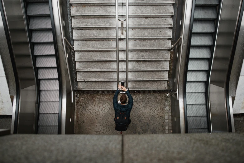 a man standing at the bottom of an escalator, by Tobias Stimmer, pexels contest winner, happening, phone photo, drone photograph, unsplash 4k, outdoor staircase