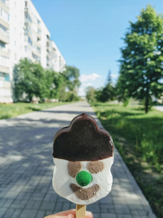 a person holding an ice cream on a stick, by Attila Meszlenyi, green head, neo norilsk, 🚿🗝📝, profile image