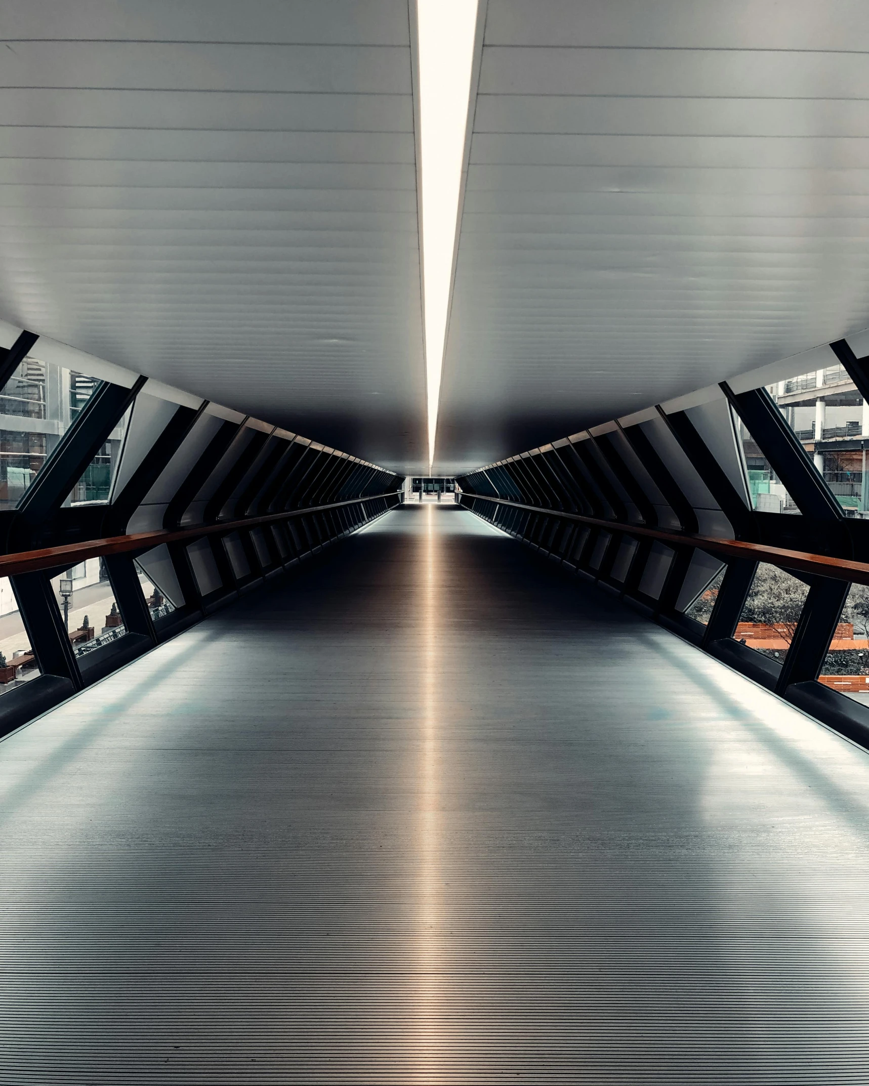 a long walkway in the middle of a city, inspired by Zaha Hadid, unsplash contest winner, light and space, bright lit interiors, on a bridge, angle view, norman foster