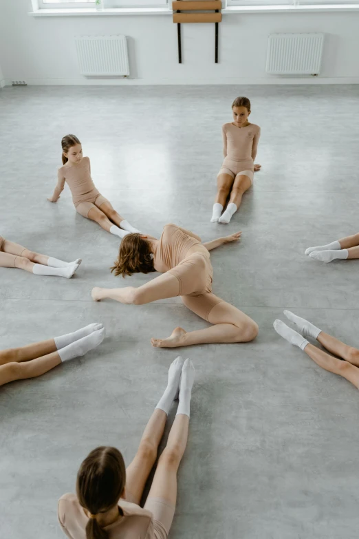 a group of people sitting in a circle on the floor, an album cover, inspired by Vanessa Beecroft, trending on unsplash, arabesque, ballet dancer, ignant, school class, issey miyake