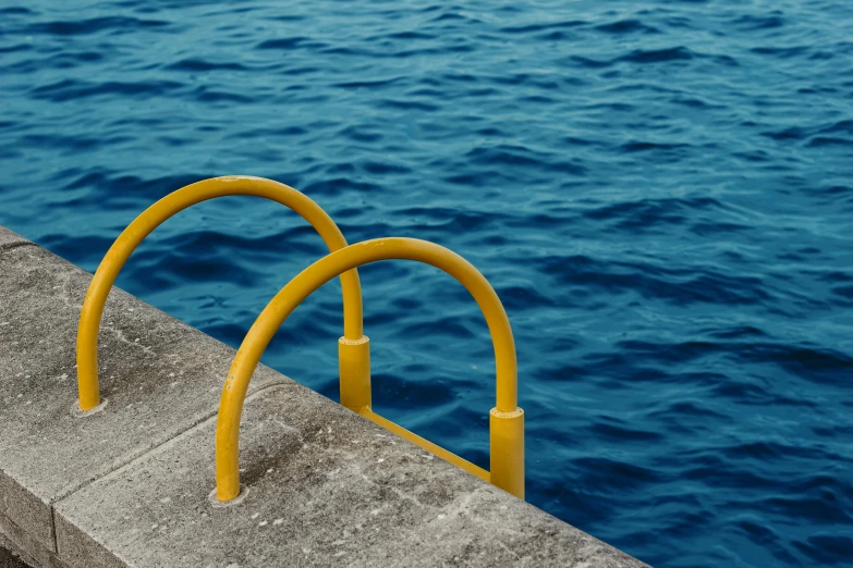 a yellow railing next to a body of water, minimalism, deep blue water, thumbnail, aquatic devices, 400 steps