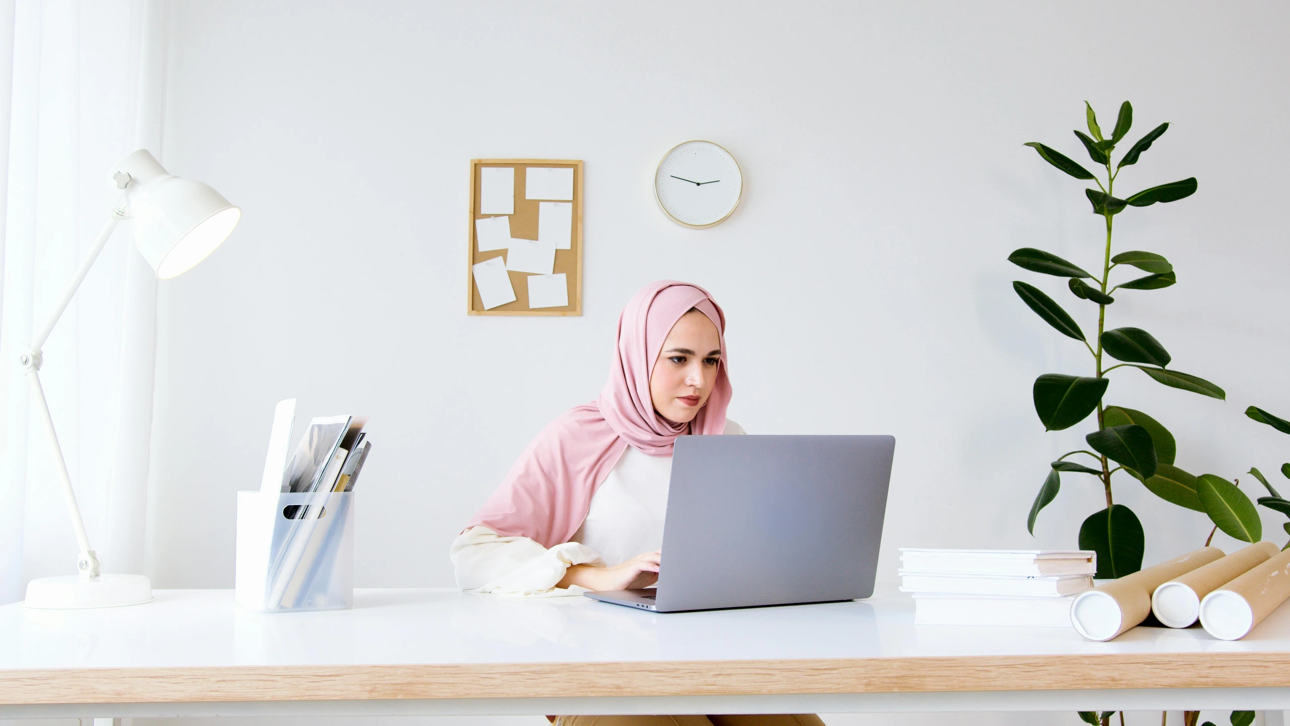 a woman sitting at a desk with a laptop, inspired by Maryam Hashemi, trending on pexels, hurufiyya, white and pink cloth, gif, malaysian, single subject