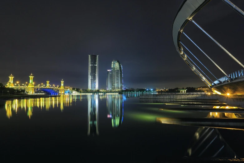 a bridge over a body of water at night, inspired by Zha Shibiao, pexels contest winner, hurufiyya, russian city of the future, complex buildings, kuala lumpur, capital of estonia