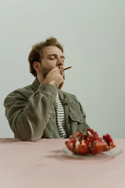 a man sitting at a table with a plate of pomegranates, an album cover, inspired by Elsa Bleda, trending on pexels, he is smoking a cigarette, fight with strawberries, thoughtful pose, h3h3