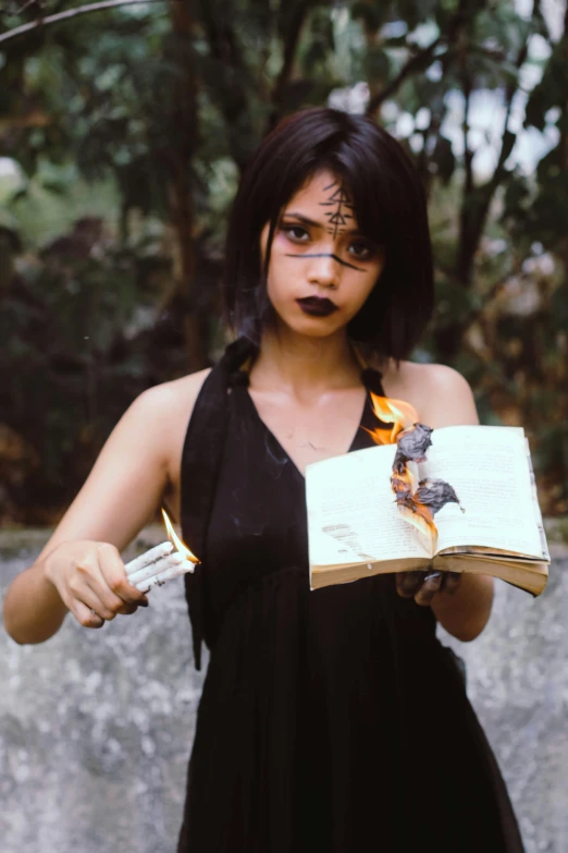 a woman in a black dress holding a book, an album cover, pexels contest winner, casting a fire spell, 2 0 0 0's photo, headshot, cindy avelino