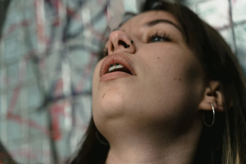 a woman standing in front of a graffiti covered wall, a hyperrealistic painting, by Attila Meszlenyi, pexels contest winner, hyperrealism, closeup. mouth open, looking at the ceiling, dreaming of kissing a girl, double chin