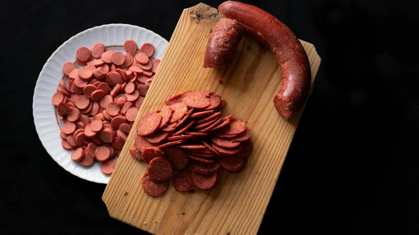 a wooden cutting board topped with slices of sausage, a portrait, by Jens Søndergaard, pexels, art nouveau, polka dot, dark red, 3 / 4 wide shot, malaysian