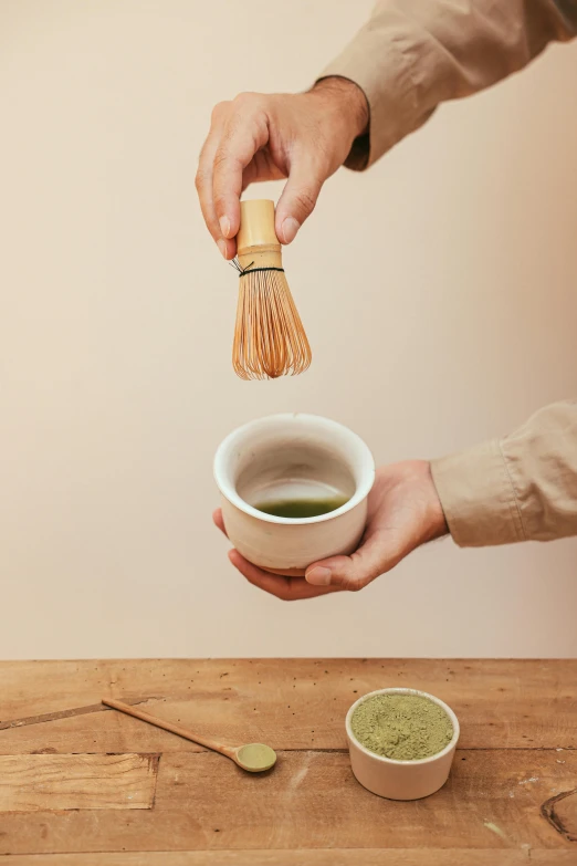 a person holding a whisk over a cup of green tea, inspired by Kanō Shōsenin, press shot, porcelain organic, made of bamboo, powder