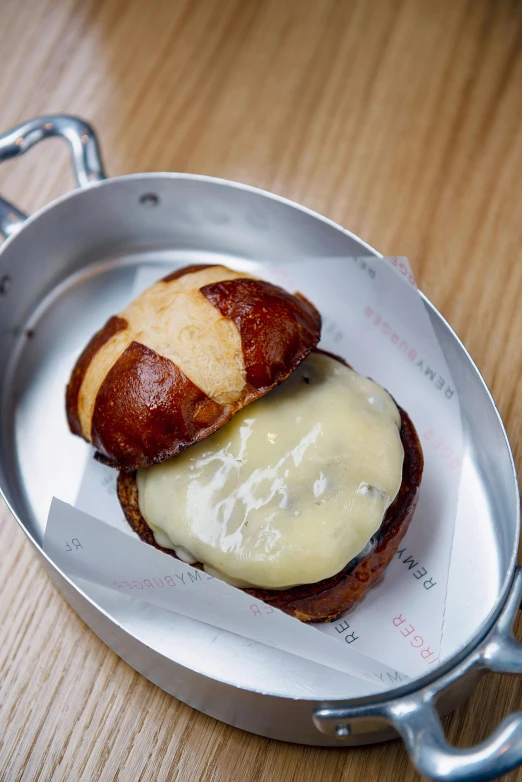 a bacon and cheese sandwich in a pan on a table, by Nina Hamnett, holding toasted brioche bun, hartper's bazaar, bao pnan, buxom