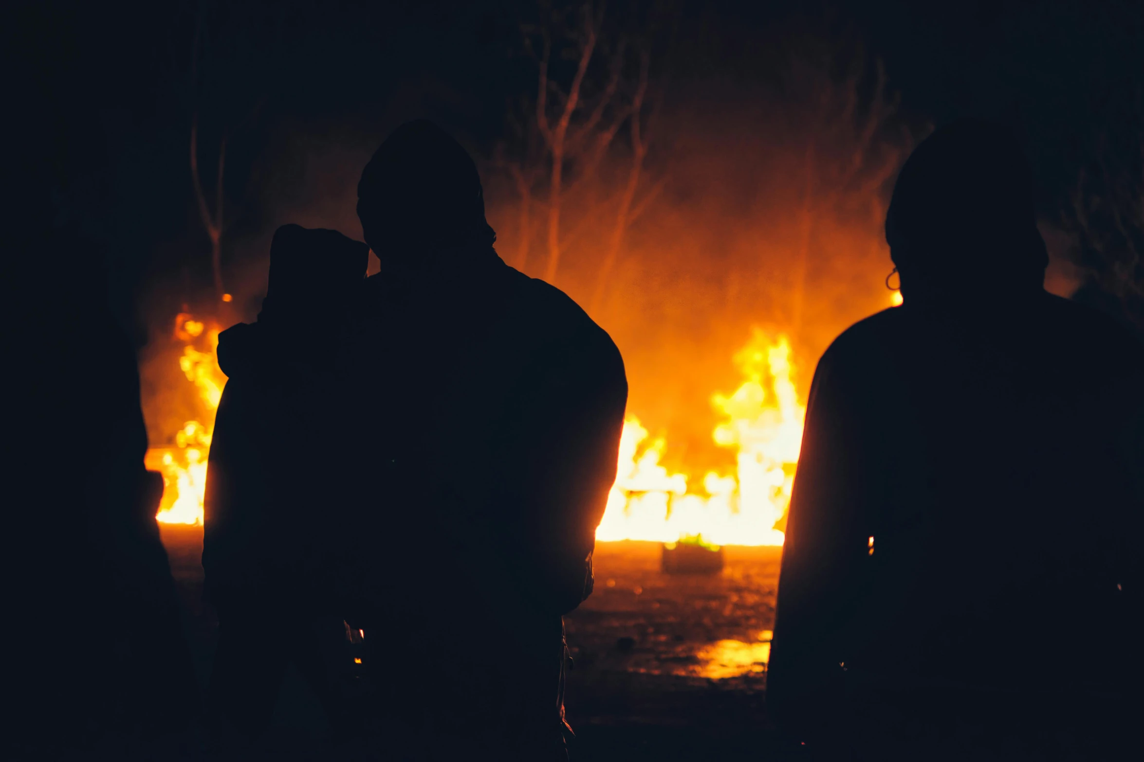 a group of people standing in front of a fire, profile image, during the night